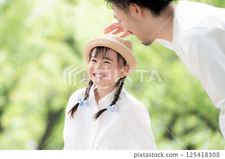 Little girl smiling outdoors together with dad among greenery Little girl smiling outdoors together with dad among greenery 125418308