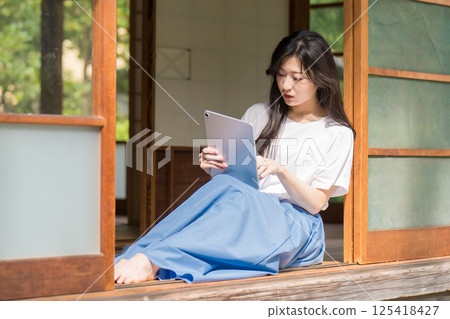 A young woman looking at a tablet and touching it 125418427