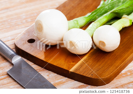 Whole green young onion bulbs on wooden desk Whole green young onion bulbs on wooden desk 125418736