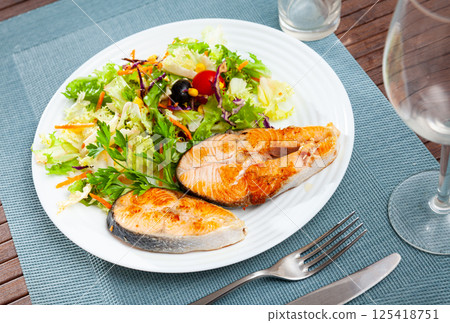 Two fried salmon steaks with vegetable salad 125418751