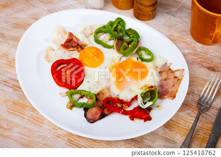 Scrambled eggs with bacon and vegetables served on plate Scrambled eggs with bacon and vegetables served on plate 125418762