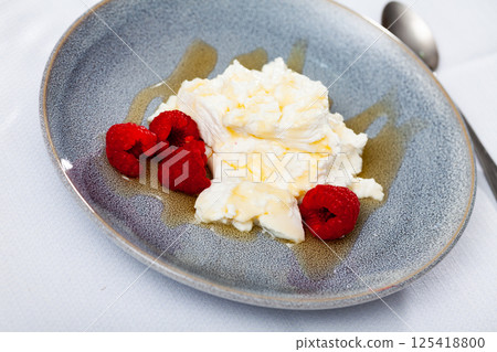 Mato served with honey and raspberries on plate 125418800