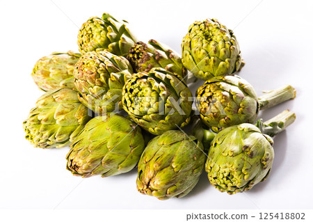 Uncooked green artichokes on a white surface Uncooked green artichokes on a white surface 125418802