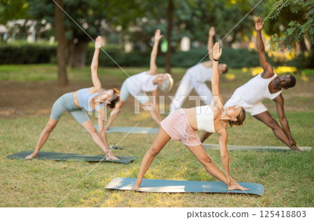 People of different ages and nationalities practice various yoga poses in summer garden People of different ages and nationalities practice various yoga poses in summer garden 125418803