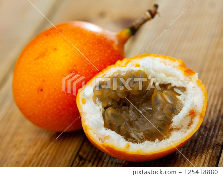 Fresh sweet granadilla whole and halves on wooden table Fresh sweet granadilla whole and halves on wooden table 125418880
