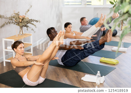 Young woman doing pilates in group in studio Young woman doing pilates in group in studio 125418919