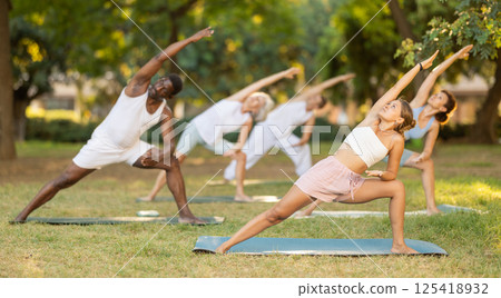 People of different ages and nationalities practice various yoga poses in summer garden People of different ages and nationalities practice various yoga poses in summer garden 125418932