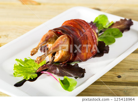 Photography of plate with baked in bacon quail with balsamic sauce 125418964
