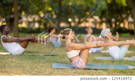Athletic men and women of different nationalities warm up together before doing yoga in summer park Athletic men and women of different nationalities warm up together before doing yoga in summer park 125418972