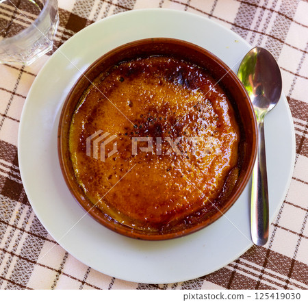 Crema catalana - dessert of Catalonia served with spoon in clay bowl. Spanish dish Crema catalana - dessert of Catalonia served with spoon in clay bowl. Spanish dish 125419030