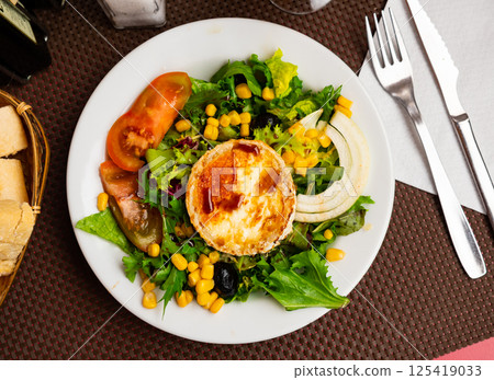 Salad with toasted soft cheese from goat milk with fresh vegetables, corn and nuts Salad with toasted soft cheese from goat milk with fresh vegetables, corn and nuts 125419033