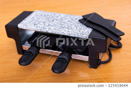Table-top grill involved in serving swiss dish of raclette Table-top grill involved in serving swiss dish of raclette 125419044