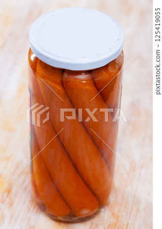 Tinned sausages in glass jar on a wooden table Tinned sausages in glass jar on a wooden table 125419055