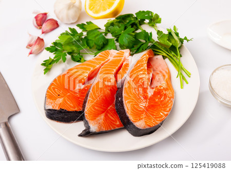 Raw salmon steaks on plate, over white background Raw salmon steaks on plate, over white background 125419088
