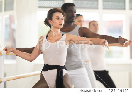 Group of dancers doing plie at barre 125419105