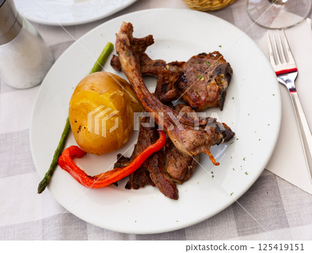 Roasted lamb ribs, pepper and potato slices served 125419151