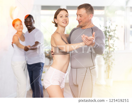 Positive young woman and adult man dancing as couple in dance studio 125419251