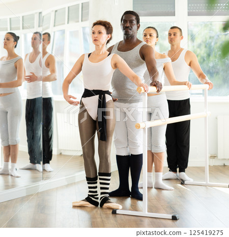 Group of dancers stand in first position at barre Group of dancers stand in first position at barre 125419275