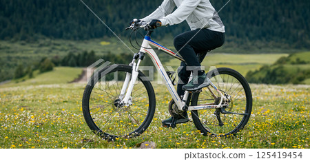 Riding mountain bike on flowering grassland mountain top 125419454