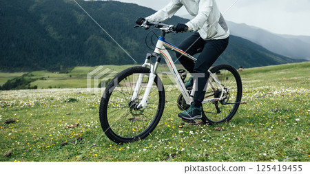 Riding mountain bike on flowering grassland mountain top 125419455