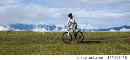 Asian woman riding mountain bike on beautiful mountain top 125419456