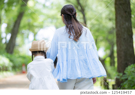 Back view of mother and daughter walking hand in hand in the park 125419457