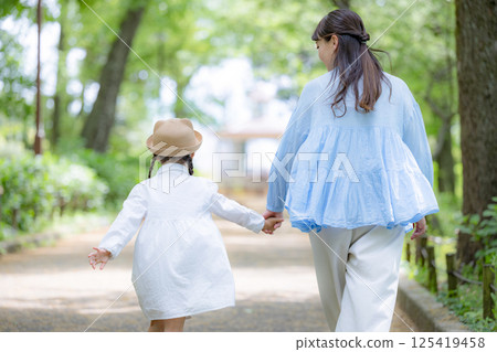 Back view of mother and daughter walking hand in hand in the park 125419458