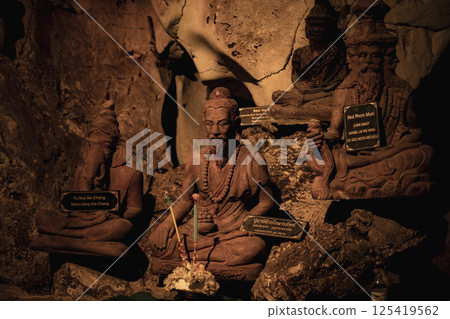 Lopburi, Thailand, April 14, 2025, Lopburi's ancient Wat Tamtako features intricately carved statues, highlighting spiritual devotion amidst a serene cave setting in Thailand 125419562