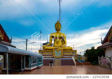 Nakhon Sawan, Thailand, November 11, 2023, Spectacular golden Buddha statue at Wat Khiriwong against a vibrant sky Nakhon Sawan, Thailand, November 11, 2023, Spectacular golden Buddha statue at Wat Khiriwong against a vibrant sky 125419598