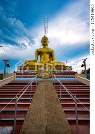 Nakhon Sawan, Thailand, November 11, 2023, Golden Buddha statue at Wat Khiriwong captures serene beauty against a dramatic sky Nakhon Sawan, Thailand, November 11, 2023, Golden Buddha statue at Wat Khiriwong captures serene beauty against a dramatic sky 125419600