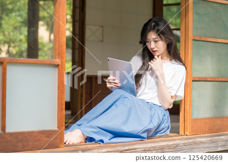 一位年輕女子手裡拿著平板電腦思考 125420669
