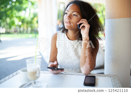 Young black woman with vitiligo using smartphone Young black woman with vitiligo using smartphone 125421110