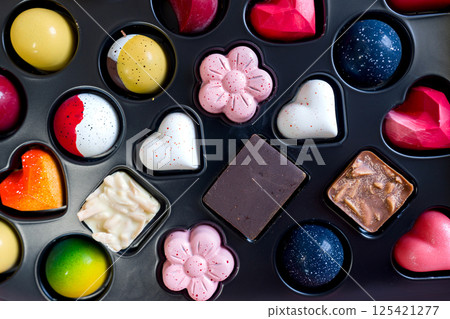 Selection chocolate with vibrant design and color fill a decorative box. Heart shape dominate, perfect for gift or treat during celebration, inviting delight and indulgence. 125421277