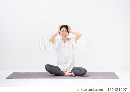 Woman doing yoga, middle-aged, holding head 125421407