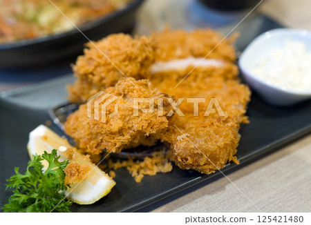 Fried oyster and loin katsu set served on black plate with a bowl of rice 125421480