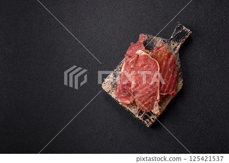 Jerky, dried pork meat slices with salt and spices 125421537