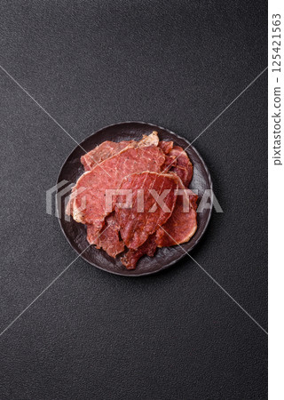 Jerky, dried pork meat slices with salt and spices Jerky, dried pork meat slices with salt and spices 125421563