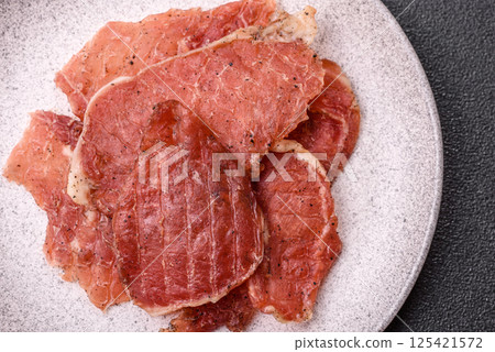 Jerky, dried pork meat slices with salt and spices Jerky, dried pork meat slices with salt and spices 125421572