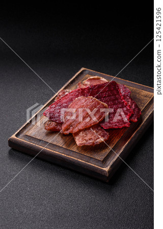 Jerky, dried pork meat slices with salt and spices Jerky, dried pork meat slices with salt and spices 125421596