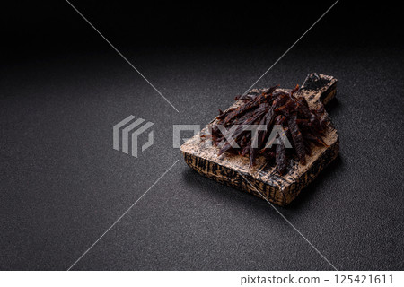 Jerky, dried horse meat or beef slices with salt and spices Jerky, dried horse meat or beef slices with salt and spices 125421611