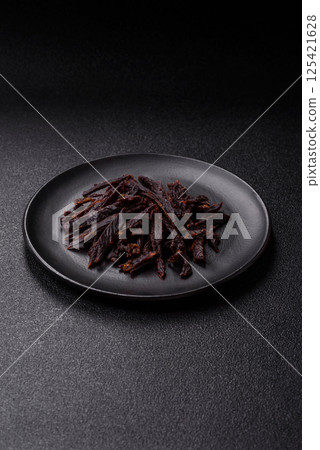 Jerky, dried horse meat or beef slices with salt and spices Jerky, dried horse meat or beef slices with salt and spices 125421628