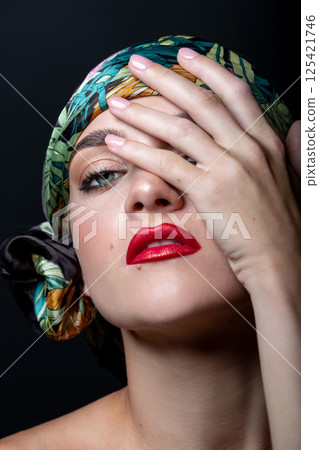 Woman with make-up and scarf on her head studio portrait Woman with make-up and scarf on her head studio portrait 125421746