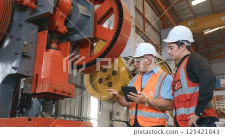 Two engineers talking together in roof steel metal manufacturing factory industry, engineering worker man standing explaining for maintain of metal sheet stamping machine, teamwork concept Two engineers talking together in roof steel metal manufacturing factory industry, engineering worker man standing explaining for maintain of metal sheet stamping machine, teamwork concept 125421843