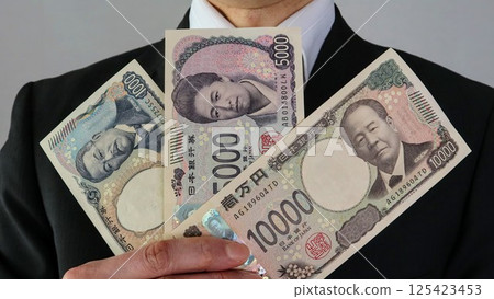 商人持有三張新日本鈔票 商人持有三張新日本鈔票 125423453