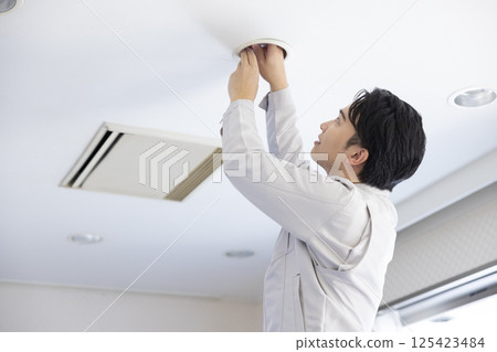 建築維護：一名身穿工作服的男子正在更換燈泡 125423484