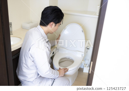 房屋銷售:一名身穿工作服的男子檢查廁所 房屋銷售:一名身穿工作服的男子檢查廁所 125423727