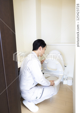 房屋銷售:一名身穿工作服的男子檢查廁所 房屋銷售:一名身穿工作服的男子檢查廁所 125423728