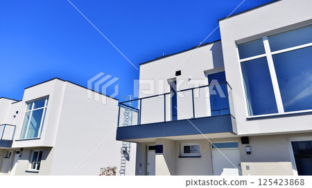 Terraced family homes in newly developed housing estate. The real estate market in the suburbs. New single family houses in a new development area. Residential homes with modern facade.  125423868