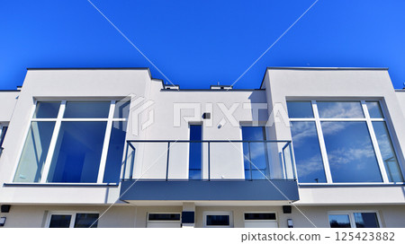 Terraced family homes in newly developed housing estate. The real estate market in the suburbs. New single family houses in a new development area. Residential homes with modern facade.  125423882