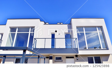 Terraced family homes in newly developed housing estate. The real estate market in the suburbs. New single family houses in a new development area. Residential homes with modern facade.  125423898